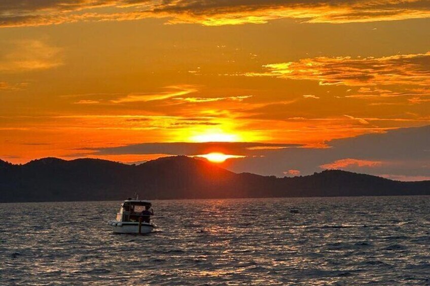 Ein Boot auf ruhigem Wasser bei Sonnenuntergang, im Hintergrund ein Gebirge. 5