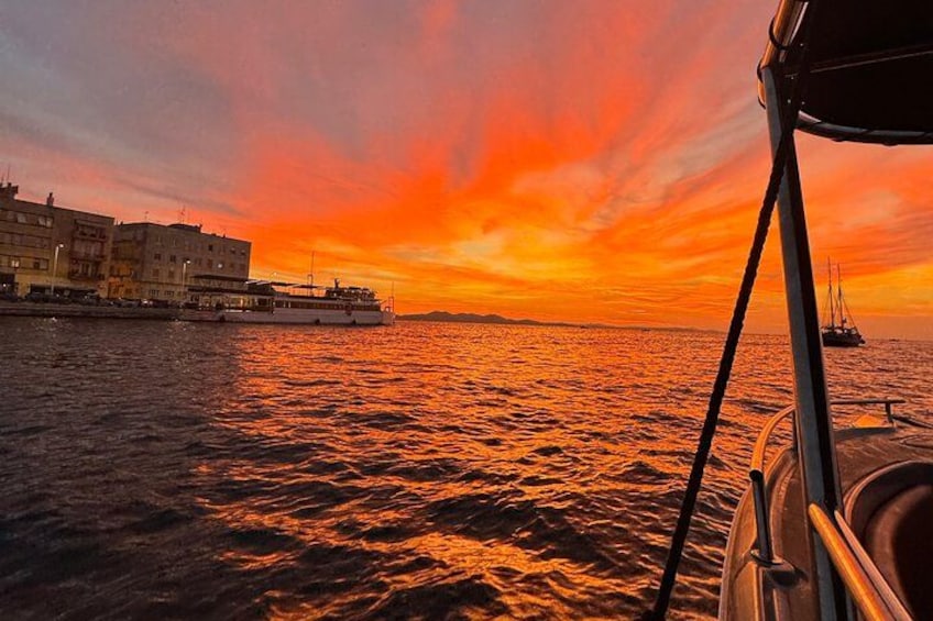 Un atardecer sobre una masa de agua, con un barco y edificios al fondo. 5