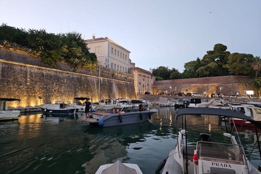 Un puerto deportivo con barcos amarrados, un muro de piedra y edificios al fondo. 2