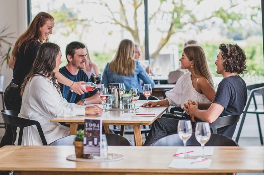 A group of people seated around a table with drinks, engaged in conversation. 1