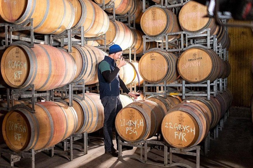 A person inspecting wooden barrels in a storage area. 5