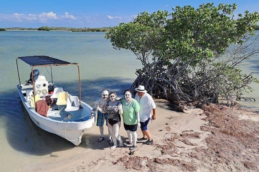 A boat on a calm body of water, a sandy beach, and a mangrove tree. 3