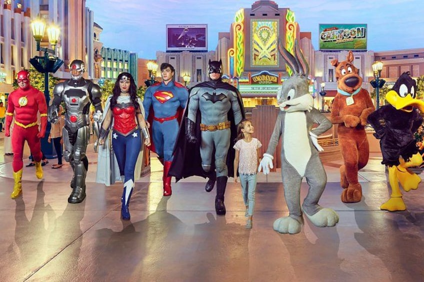 A group of superheroes and animated characters in a themed area with a large building in the background. 4