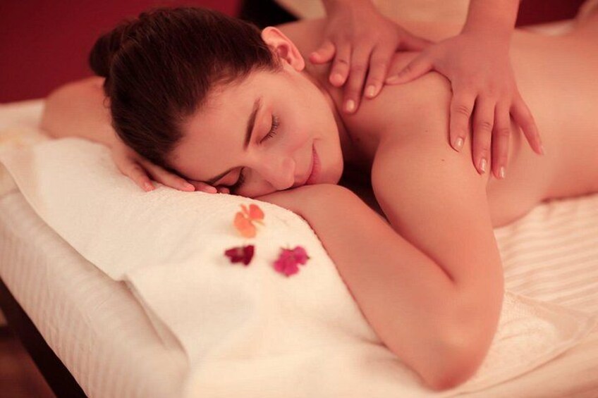 Une personne reçoit un massage sur une table de massage, et des fleurs y sont disposées. 2