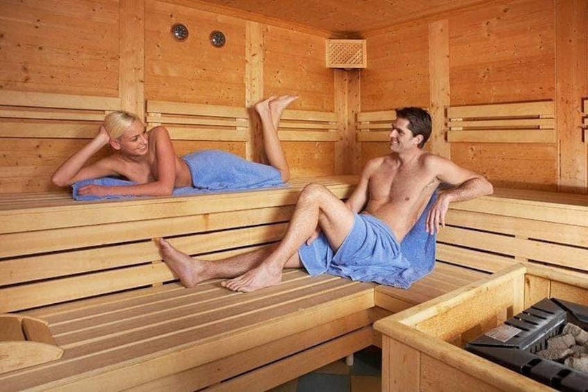 Un sauna avec des bancs en bois, un hammam et un appareil de chauffage pour sauna. 1
