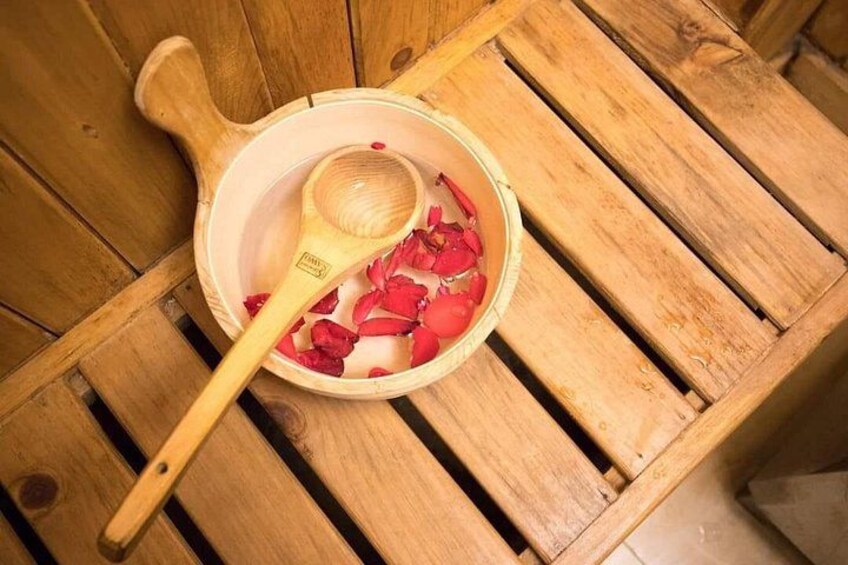 Une table en bois sur laquelle se trouve un bol rempli de pétales de rose et une cuillère en bois. 4