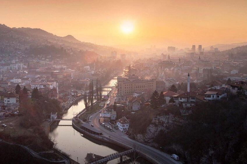 Een stadsgezicht met een rivier, een brug en een zonsondergang. 1