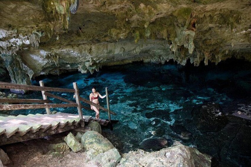 A cave with a person standing on a wooden platform over a pool of water. 4