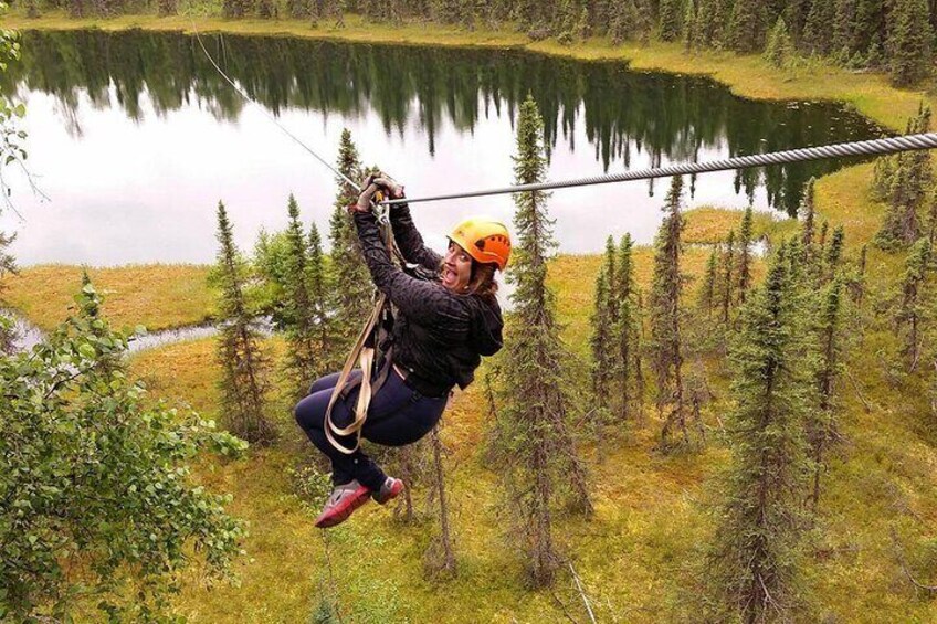 A person zip-lining over a forested area with a lake in the background. 5