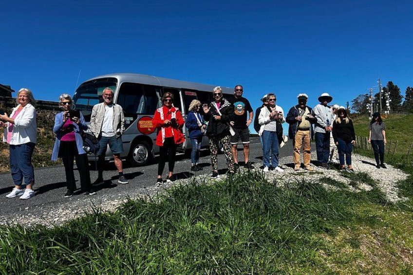 A group of people standing on a gravel path with a vehicle in the background. 2