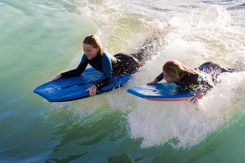 Two people surfing on blue boards in the ocean. 1