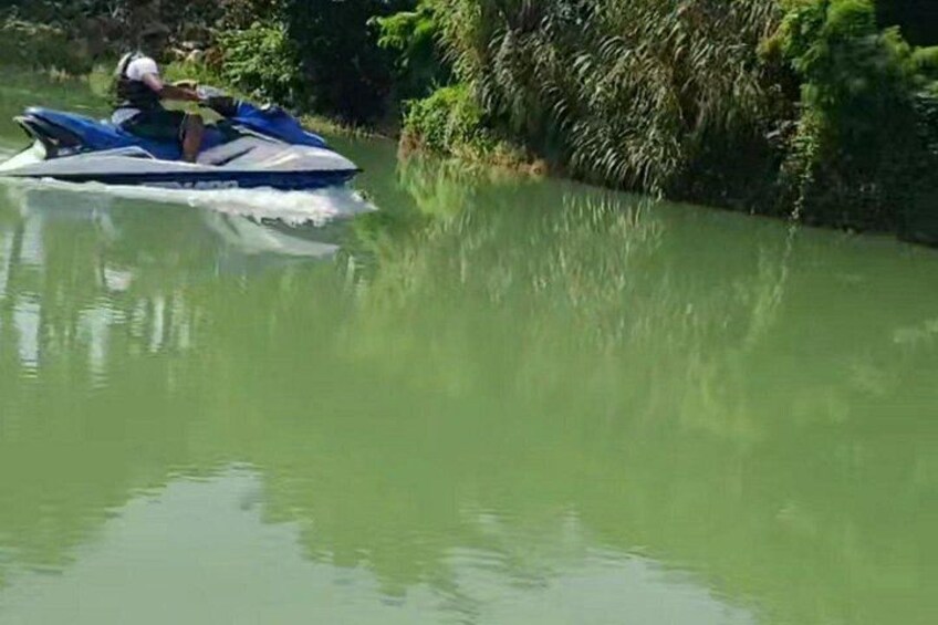A person riding a jet ski on a river surrounded by greenery. 2