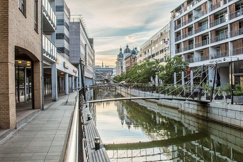 A canal with buildings on either side, a bridge, and a clear sky. 1