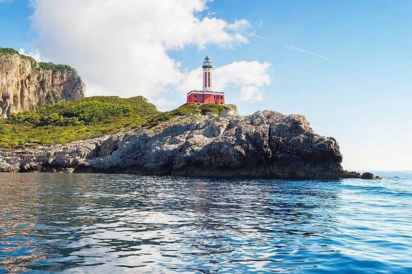 Un faro sobre un promontorio rocoso, con aguas azules y cristalinas al frente. 5