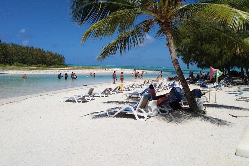 Una playa con arena blanca, palmeras y gente tomando el sol. 2