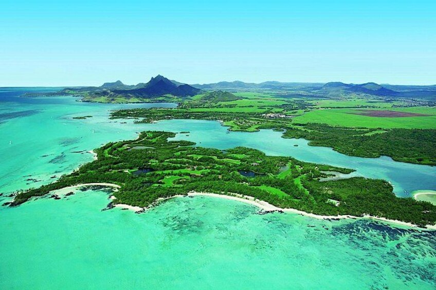 Un paisaje costero con una isla grande rodeada de aguas turquesas, una cordillera en la distancia y cielo despejado. 3