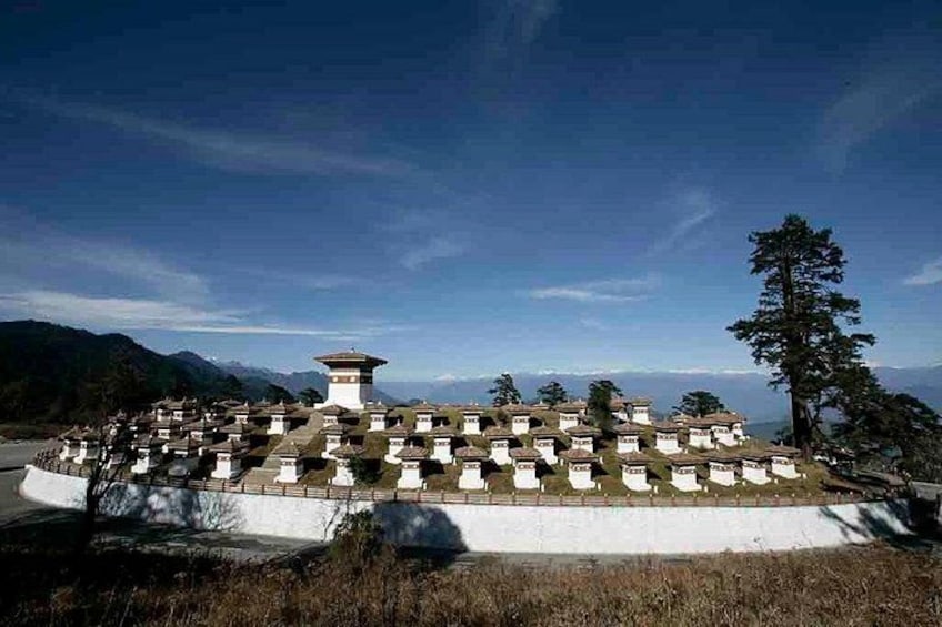 A circular arrangement of buildings with a central tower, surrounded by a natural landscape with mountains in the background. 4