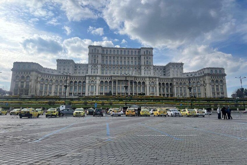 Un edificio grande y ornamentado con una plaza pavimentada al frente. 5