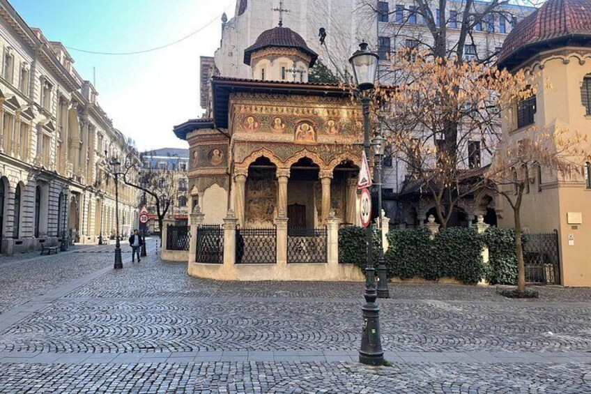 Una calle adoquinada con un edificio histórico de arquitectura ornamentada y un farol. 4