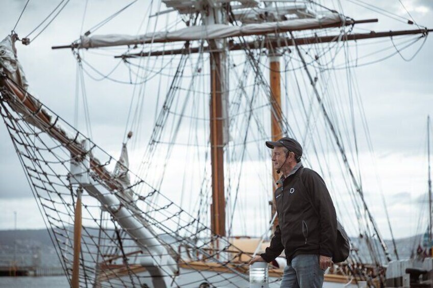 A person standing on a ship with a complex network of ropes and sails. 5