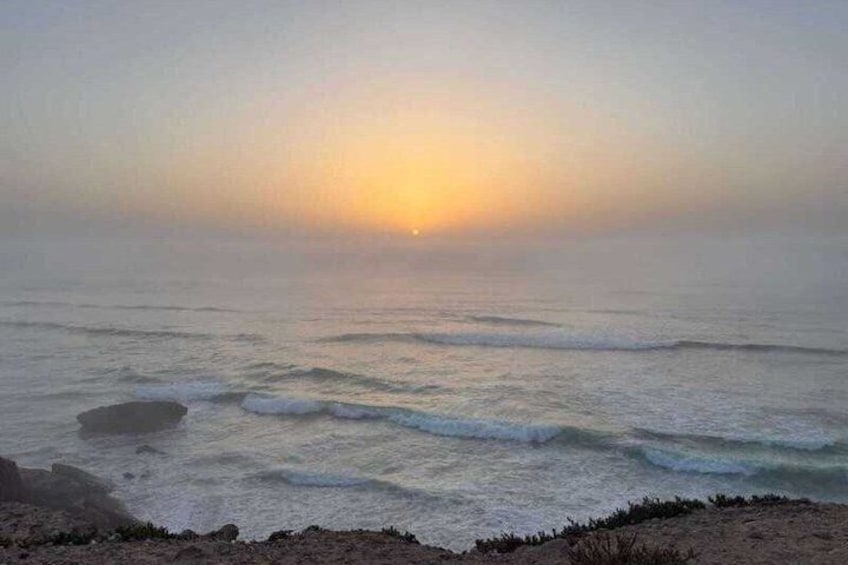 A beach at sunrise with waves and a clear sky. 5