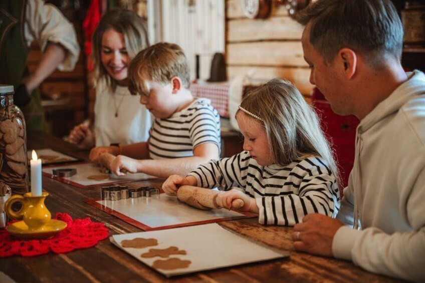 A family at a wooden table with a candle, cookie cutters, and a red doily. 5