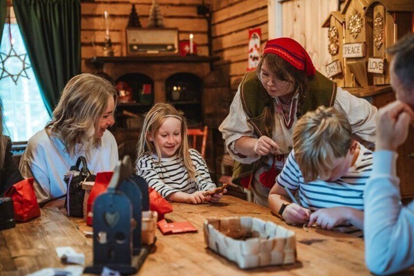 A family engaged in a craft activity at a wooden table with a Christmas tree, a candle, and a clock in the background. 4