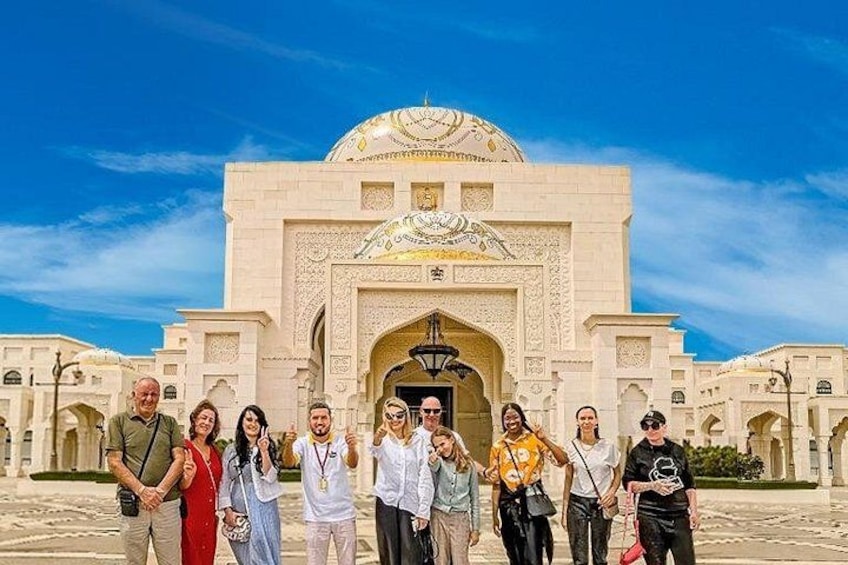A group of people standing in front of a large, ornate building with a dome and intricate architectural details. 2