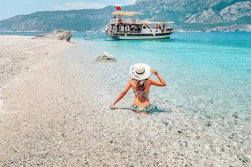 Una playa con agua cristalina, un bote y terreno rocoso. 3