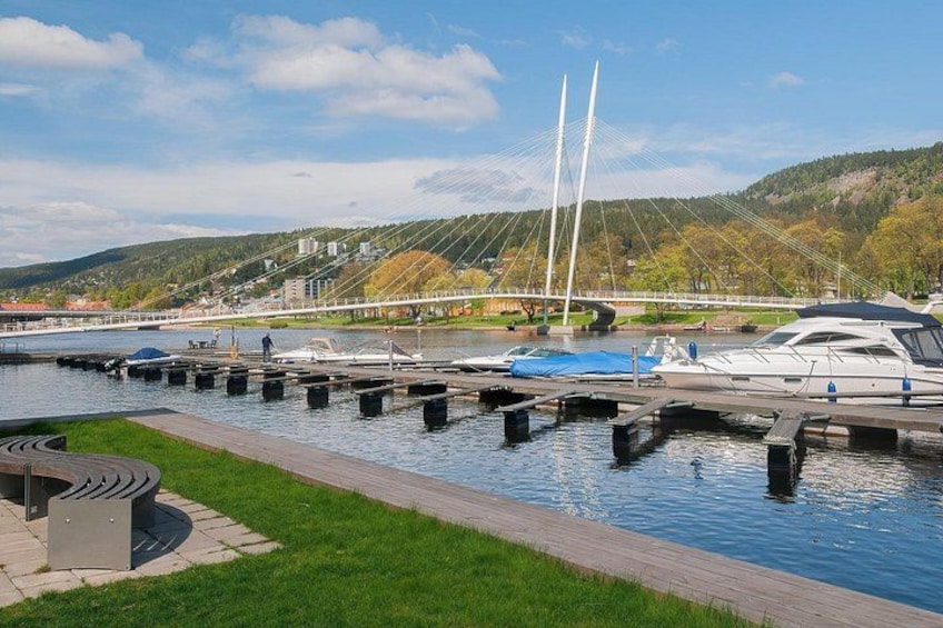 Een jachthaven met aangemeerde boten, een brug op de achtergrond en een grasveld voorop. 1