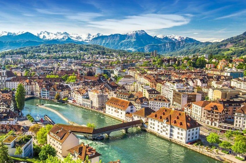 A cityscape with a river, historic buildings, and mountains in the background. 2
