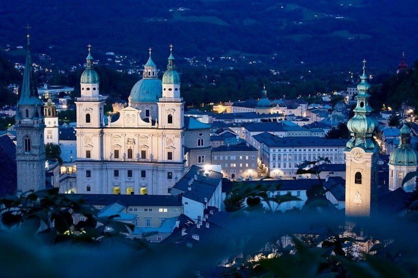 A historic cathedral with multiple domes and towers, surrounded by a town with illuminated buildings. 3