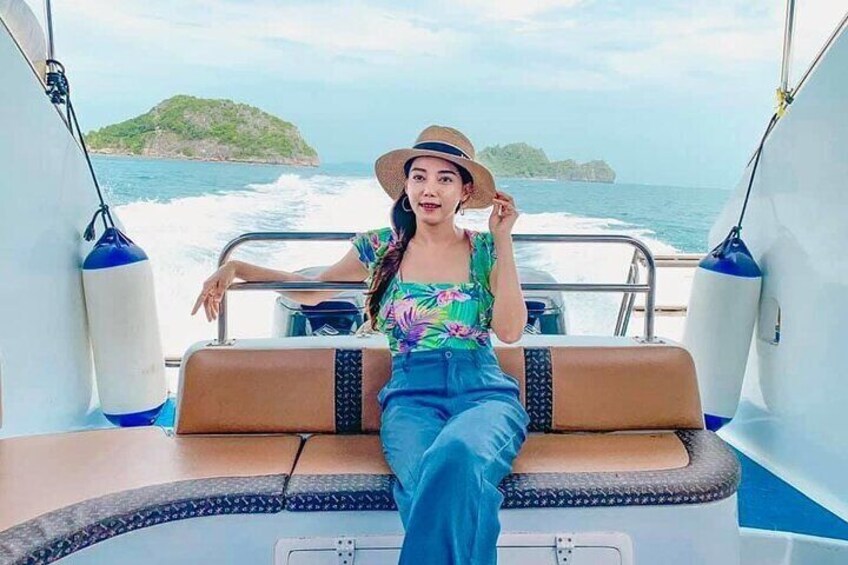 A person sitting on a boat with a view of the sea and a distant island. 3