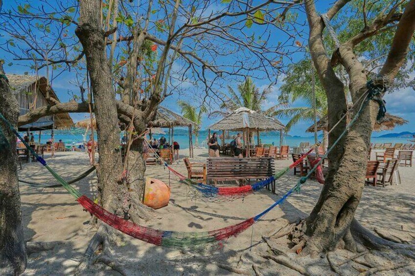 A beach with hammocks, a wooden bench, and thatched umbrellas. 5
