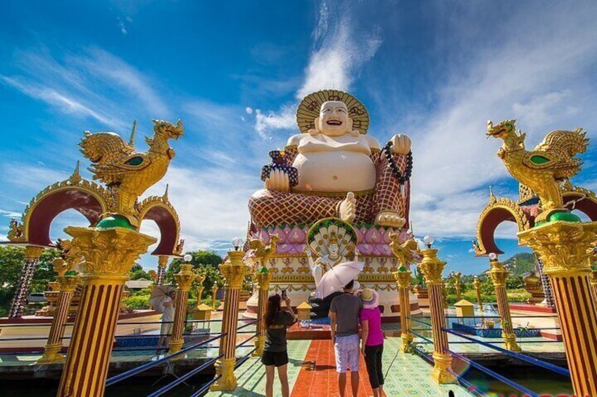 A large Buddha statue with golden dragons and a pink figure in front. 1