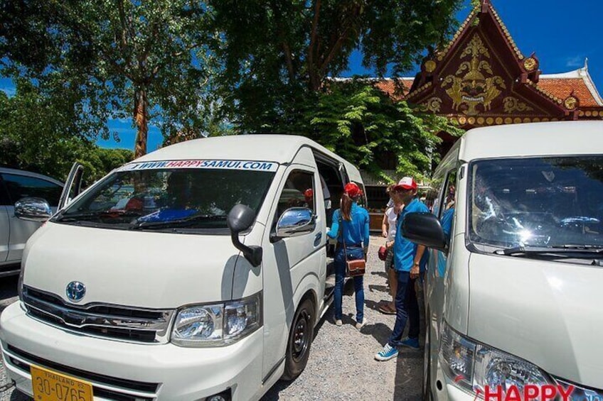 A white van with a website address on the windshield, parked in front of a building with a traditional roof. 4