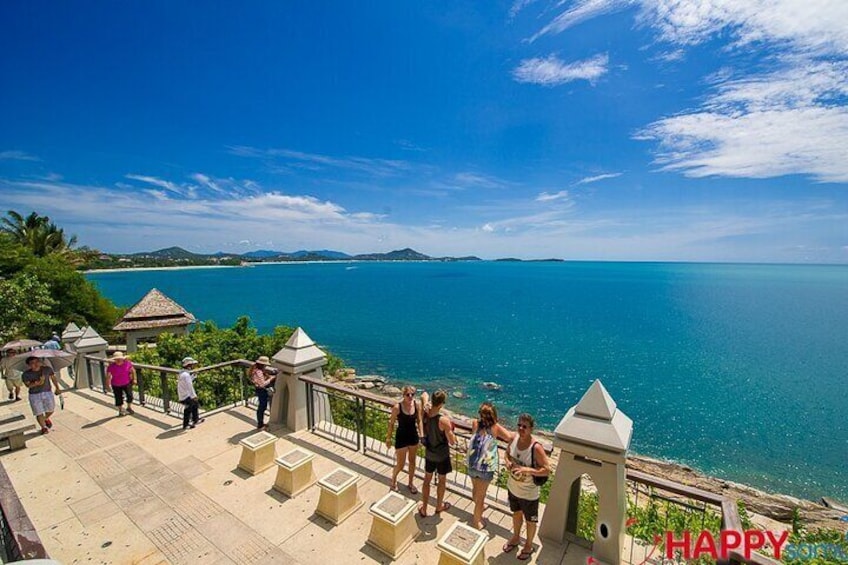 A coastal promenade with people walking, overlooking a clear blue sea and distant land. 5