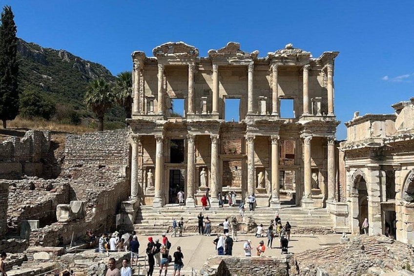 Ruinas de una estructura antigua con columnas y escalones, rodeadas de visitantes. 3