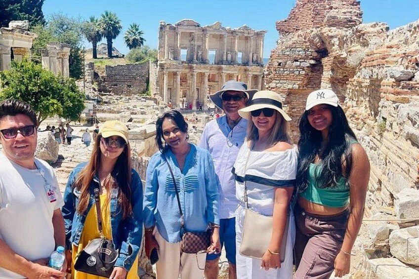 Un grupo de personas en un antiguo sitio arqueológico con ruinas y un gran edificio clásico al fondo. 4