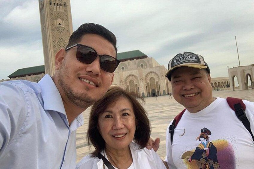 Three people in front of a large historical building with arches and a minaret. 4