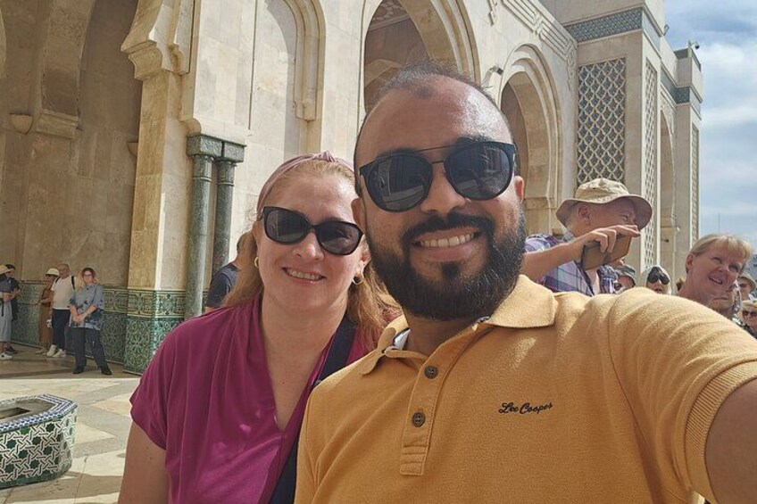 A couple taking a selfie in front of a historic building with arches and columns. 2