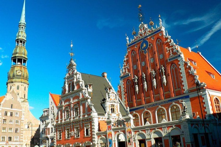 Un paisaje urbano europeo histórico con edificios ornamentados, incluyendo una iglesia roja destacada con una torre del reloj. 4