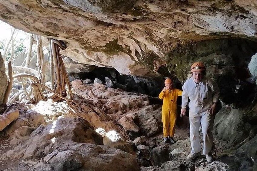 Dos personas en una cueva con formaciones rocosas y un árbol. 4