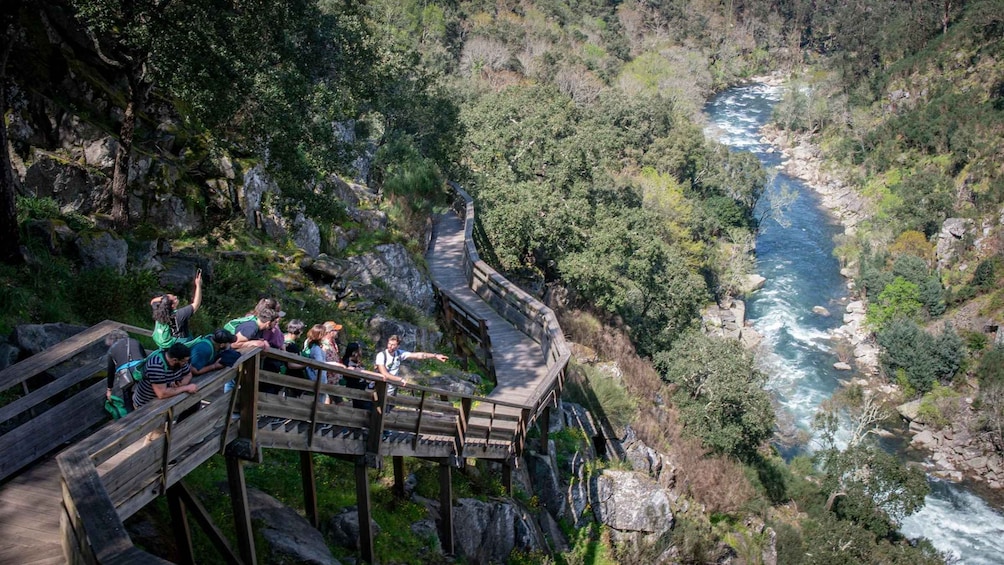 A wooden observation deck with people overlooking a river. 1