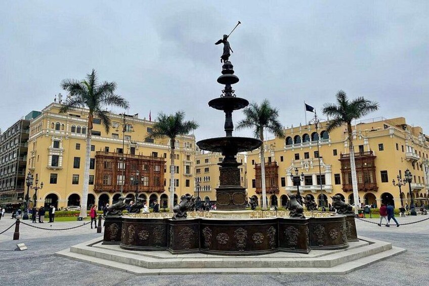 Ein Brunnen mit Statuen, umgeben von Palmen und historischen Gebäuden. 3