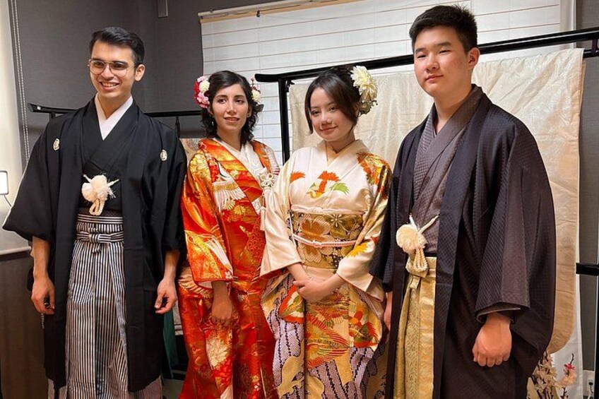 Quatre personnes, vêtues de costumes traditionnels japonais, se tiennent à l’intérieur d’un bâtiment. 1