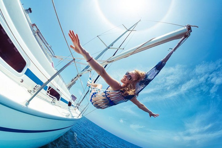 A person in a hammock on a boat, with the ocean and sky in the background. 1