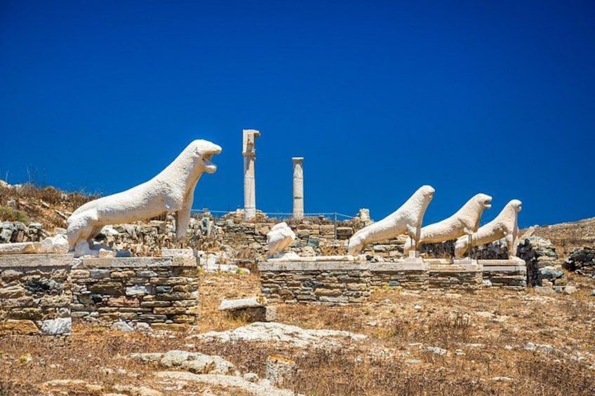 Ancient white stone lion statues on a rocky hillside with stone columns in the background. 2