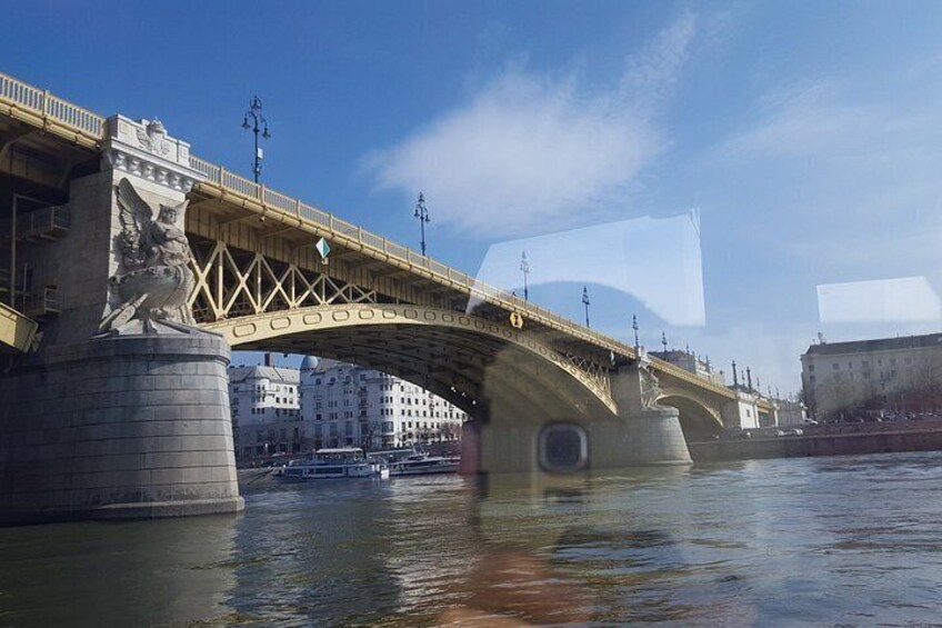 A bridge with a statue on the left, a river below, and buildings in the background. 4