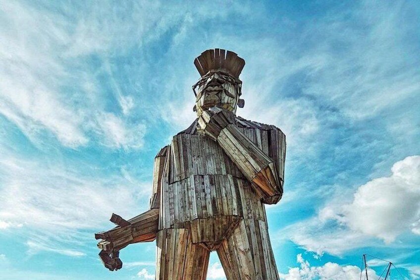 A large wooden statue of a man holding a rifle against a blue sky with clouds. 5